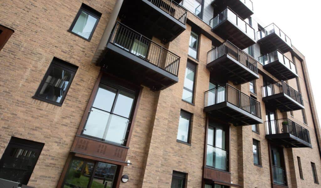 A block of apartments (flats) from the outside shows columns and rows of smart looking balconies