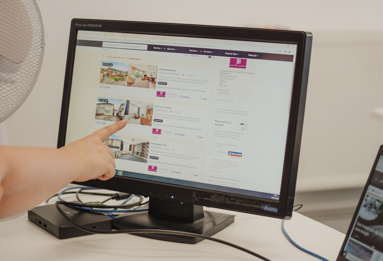 A person's hand is pointing towards a property on a property portal