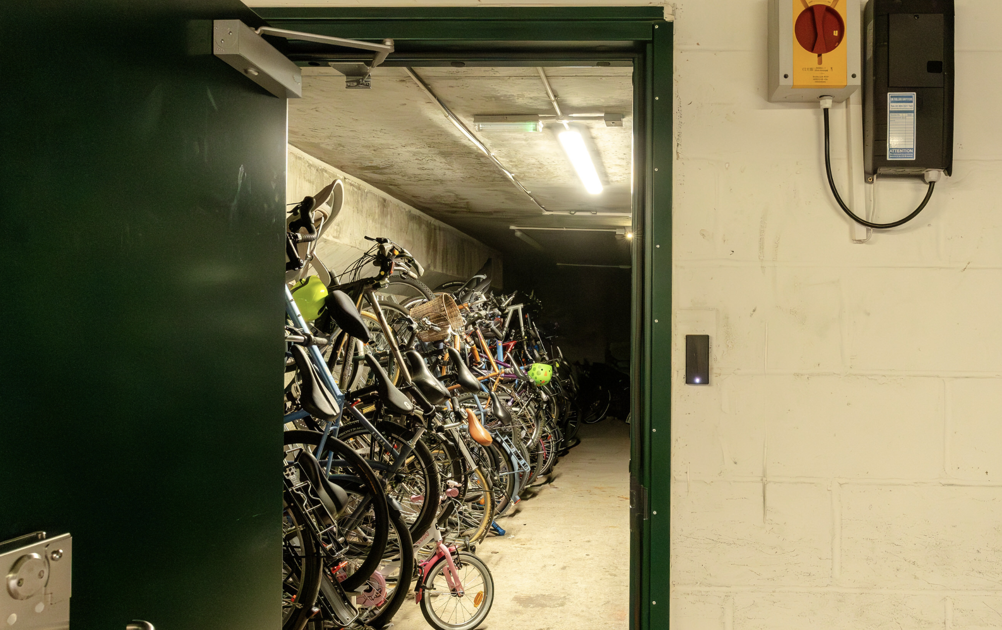 A smartly organised bike storage facility. The door has been opened to show a row of stacked, secure bikes.