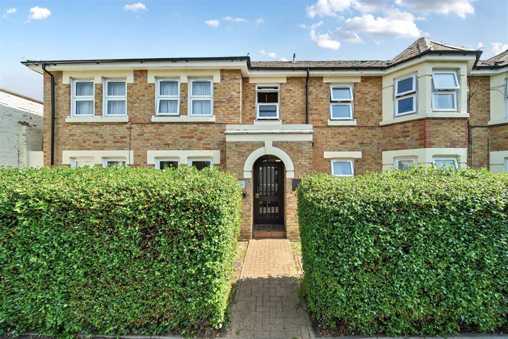 A pathway leading up to a front door. The hedges on either side are trimmed neatly.