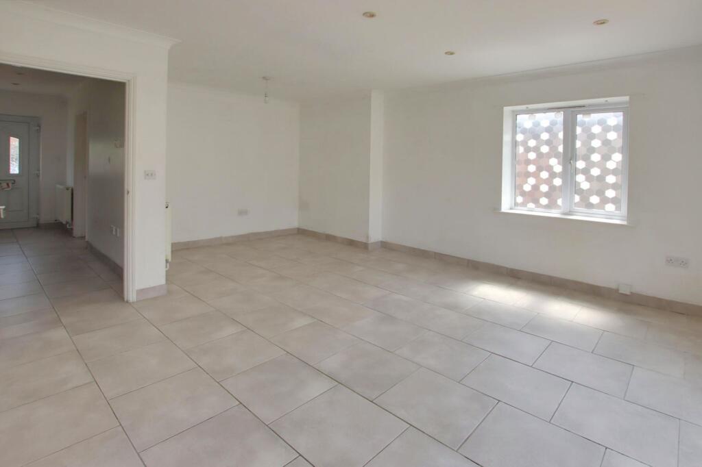 An empty tiled room with an arched doorway and a small window.