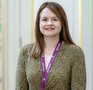 Jemima is wearing a green top and purple Jennings & Barrett lanyard as she looks into the camera.
