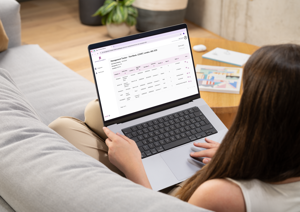 A photo of a woman sitting on a sofa as she looks through the management tracker on her laptop