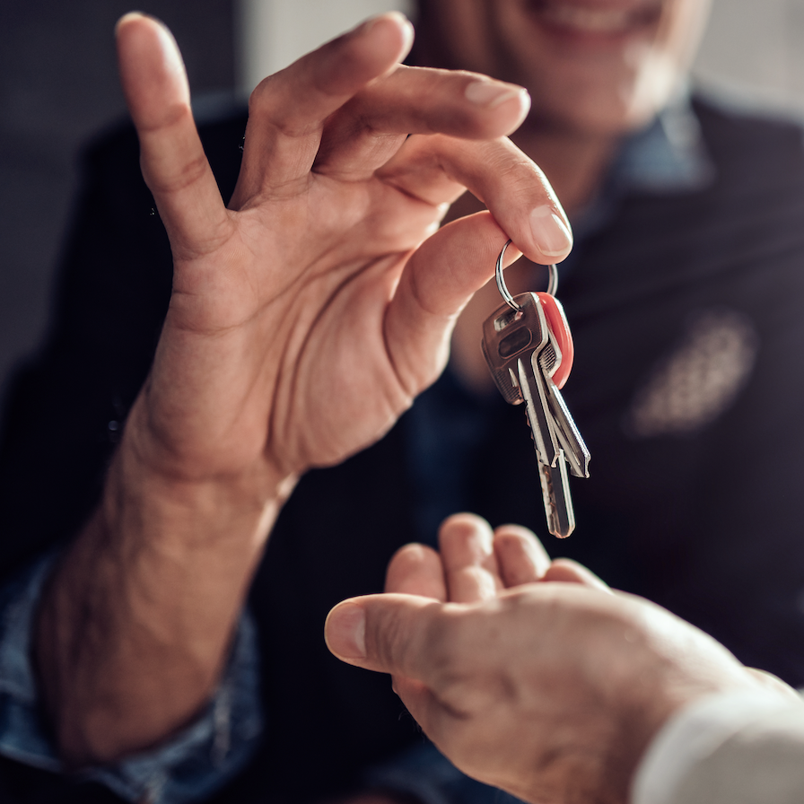 A landlord or agent is handing keys over to a man who is holding a tenancy agreement.