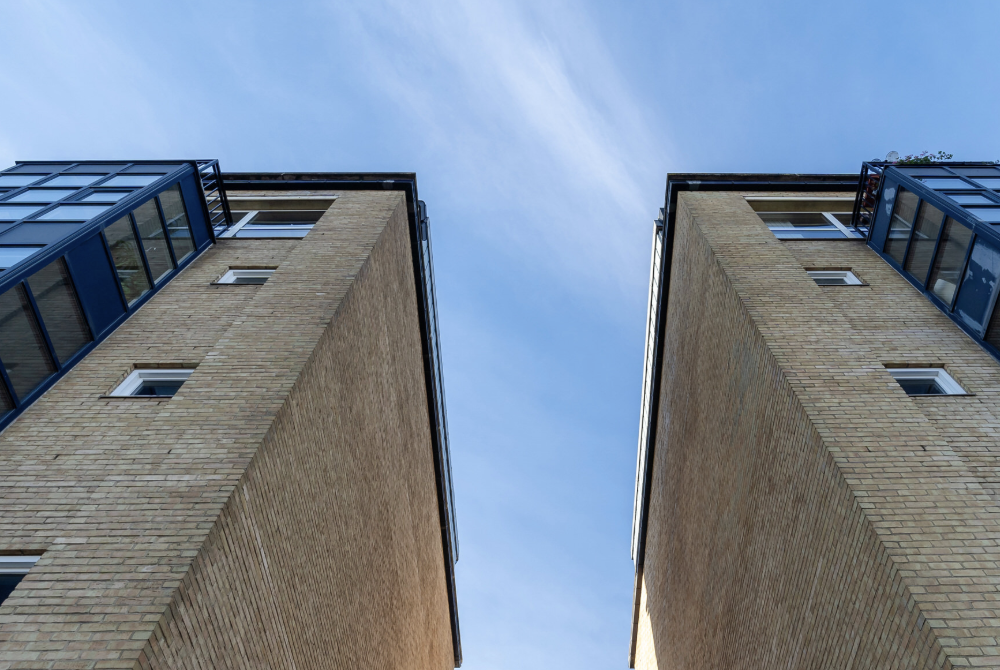 Two London high-rise apartment buildings stretch towards a blue sky