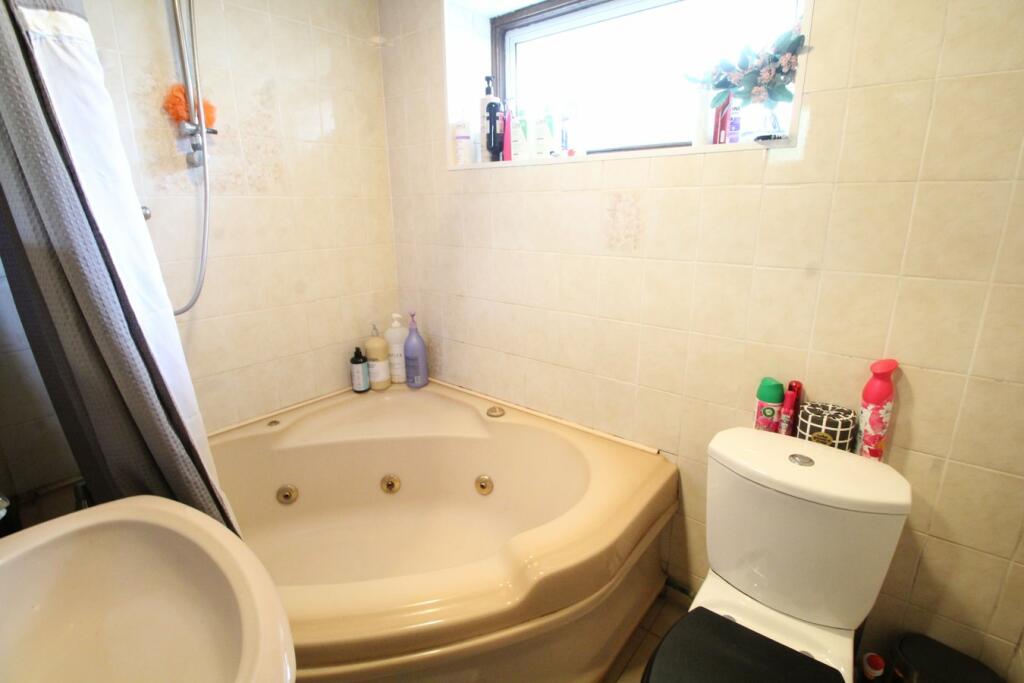 Image shows an aged bathroom with poor lighting and staging