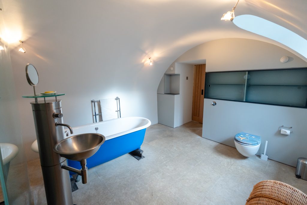 More unique design features for the family bathroom can be seen in this image, with it's stunning free-standing, industrial style sink. Lighting highlights the curved ceilings.
