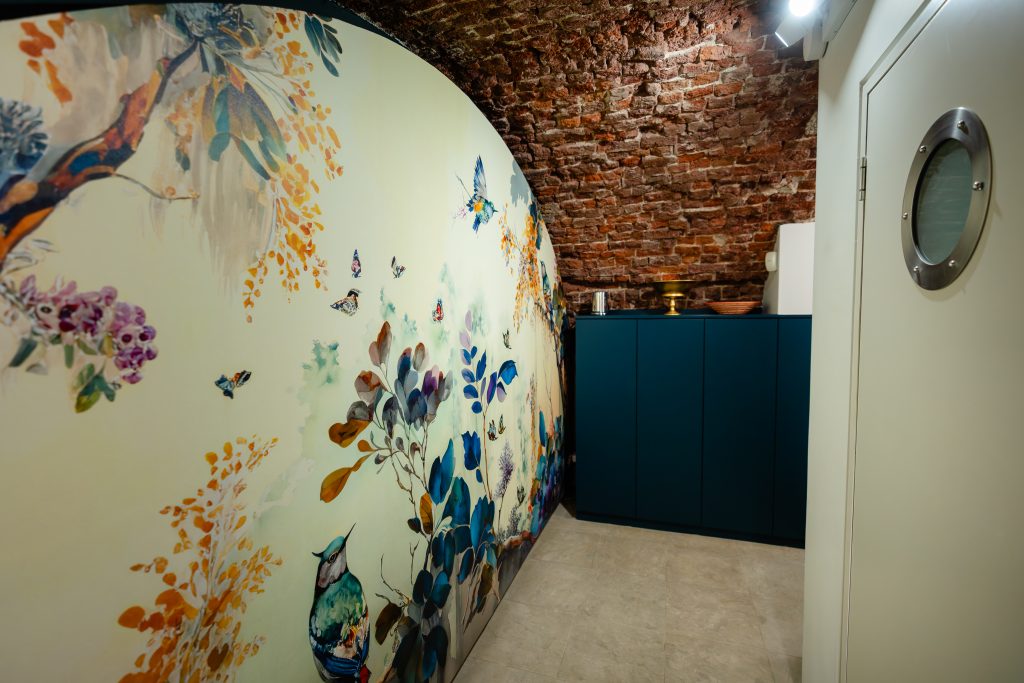 Another view of the entrance hall shows the vibrant feature wall and exposed brick curved ceilings.