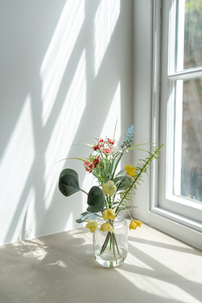 Sash windows bathe the property in lots of natural lighting. Flowers are pictured resting on the wide window frame, to show the scale of the thick exterior structure.