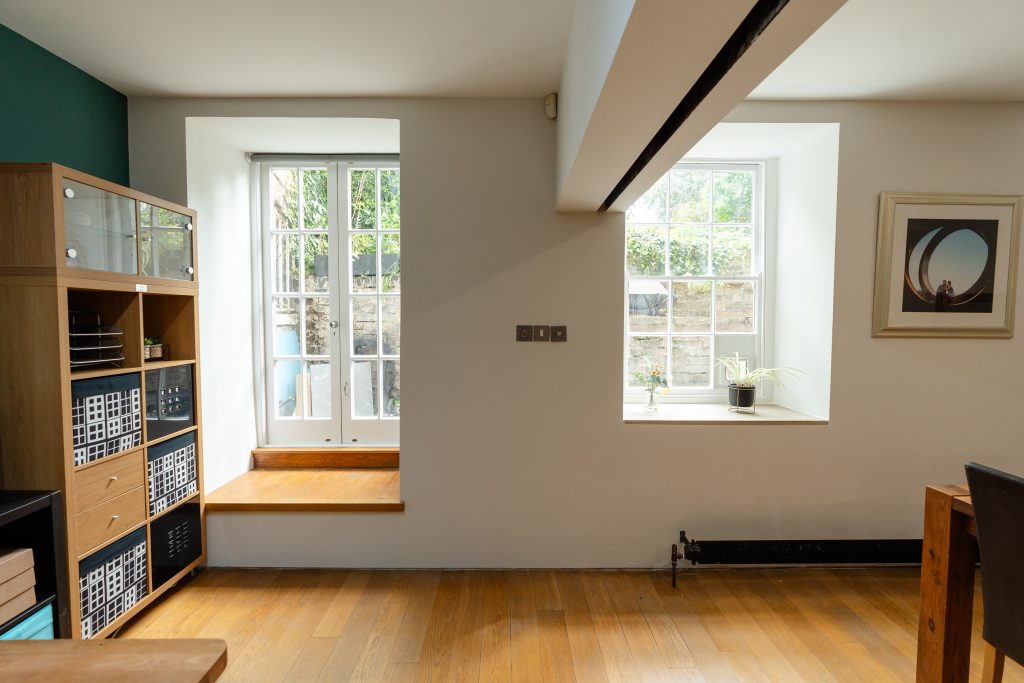 A shot of the second bedroom shows the guide for the moving media wall, a large sash window, and the doorway onto the apartment's private terrace.