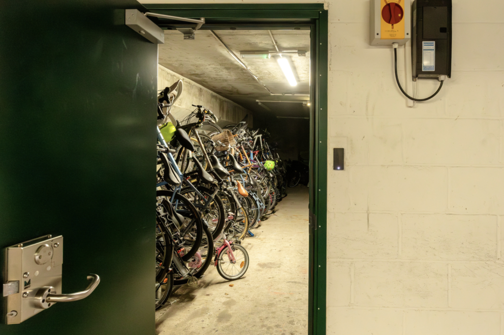 An underground bike store on the estate has an open door, showing a neat row of safely stored bicycles.