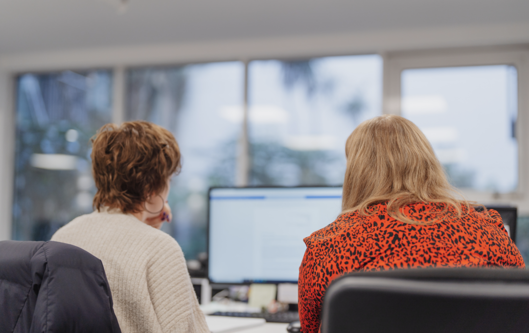 Members of our back office team working together in front of a computer